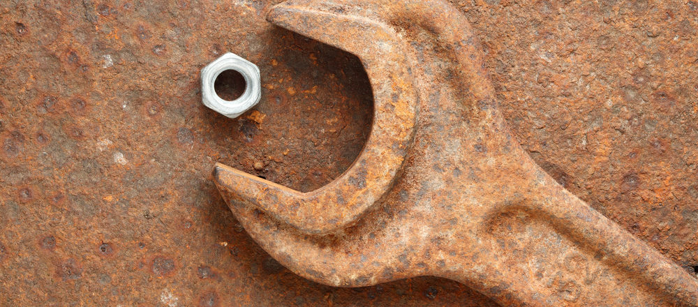 Bolt and rusty wrench on rusty background