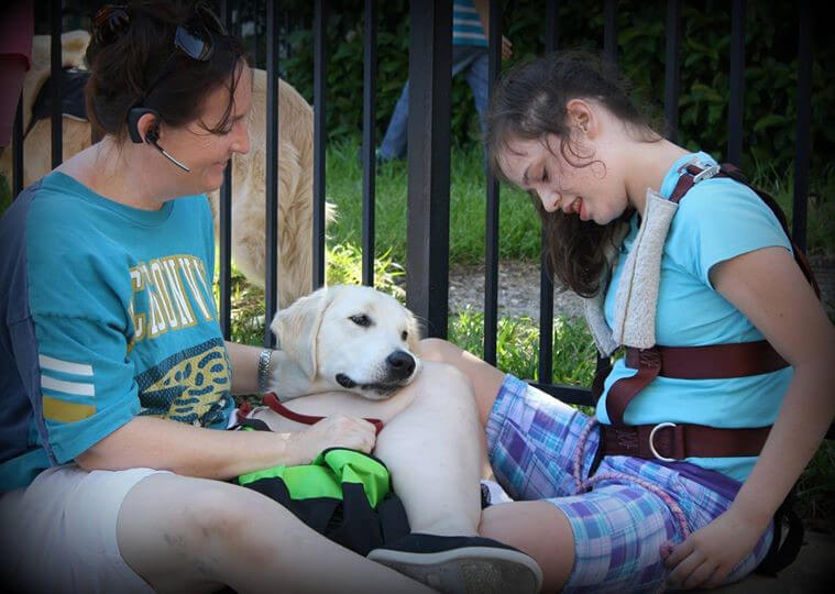 Adult and differently abled child sit with service dog