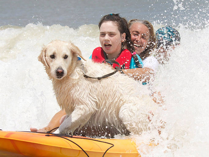 Adult and child boogie board with service dog