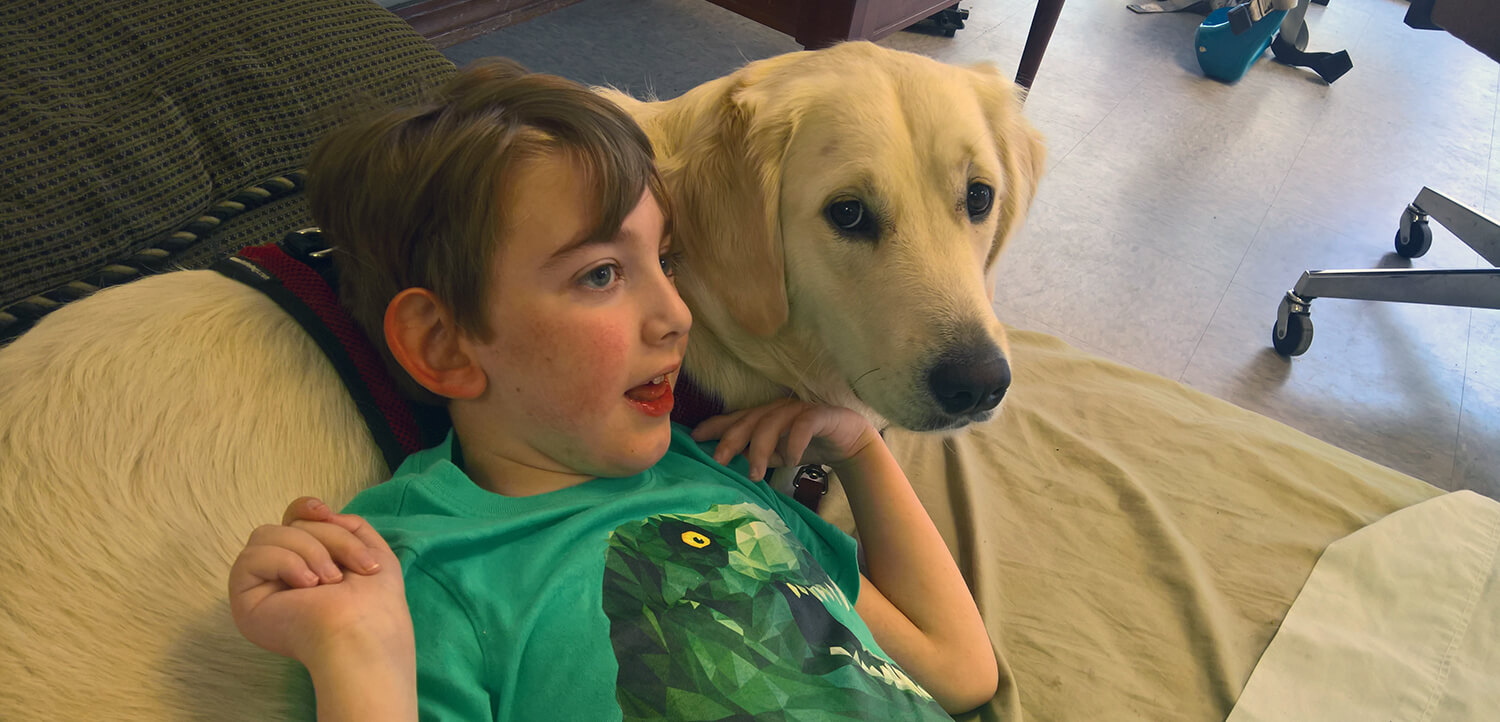 Young boy leaning on service dog