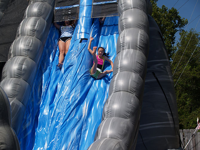 Two children slide down inflatable double slide